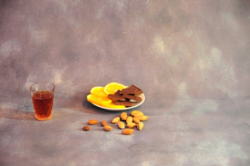 Crystal glass of cognac, a plate with lemon slices and chocolate on a gray background, rad a...