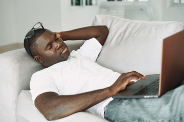 man relaxing on sofa with laptop