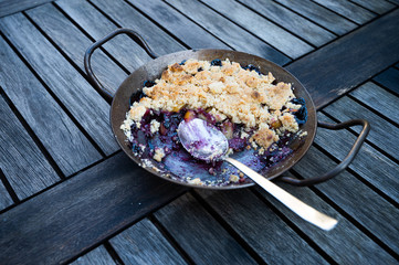 freshly baked apple blueberry crumble on a rustic wooden table with spoon