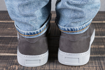 male legs with gray leather shoes, on wooden boards, concept, back