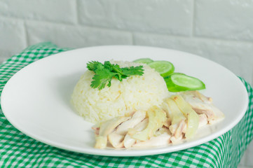 Chicken rice with dipping sauce and broth laid on a green tablecloth