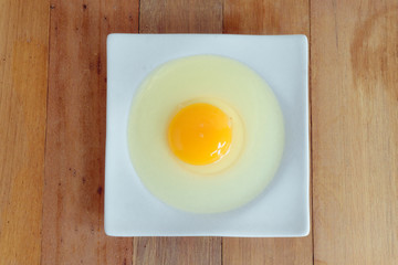 Eggs hammered on a white plate placed on a wooden table in the kitchen.top view