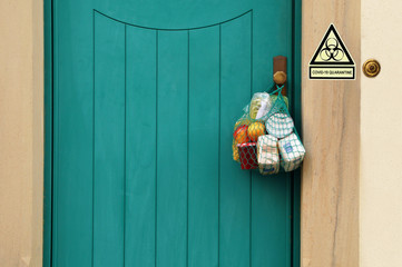 Food delivery during the quarantine. Shopping bag with Merchandise, goods and food is hanging at...