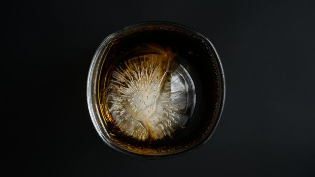 Time lapse 4k video, Round ice cubes in a glass of water with a black background cola It slowly melts.