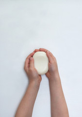 Child hands holding white soap bar. Plain white background. Isolated.
