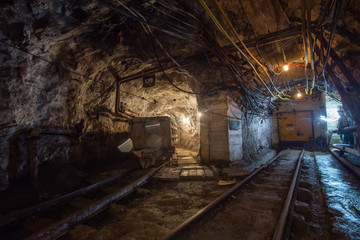 Fototapeta na wymiar Underground gold mine tunnel with light and rails
