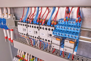 Two intermediate relays, three contactors or magnetic starters, a cross-module and terminals in the electrical Cabinet. Wires and cables are connected to electrical equipment. Assembly manufacturing.