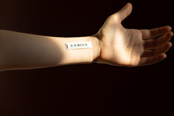 Bar code is on  a teenager's hand on the dark background. Clone of DNA and human genome. The concept child digital electronic cards, tracking during the pandemic, in quarantine. Selective focus.