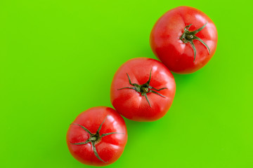 Three large red juicy fresh tomatoes lie on a green table. Close-up. Top view