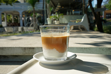 Close up glass of latte coffee with sunlight and shadow