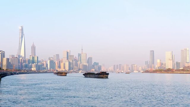 Time lapse footage of cargo ships fleet sailing on Huangpu river with Shanghai skyline cityscape background in sunny day, 4k video.