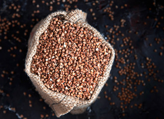 buckwheat groats in burlap sack on dark background
