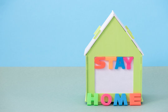 Green house with the inscription stay home in a coronavirus pandemic on paper background - Powered by Adobe