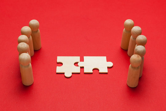 Wooden figures with pazzles on red background. Agreement between business mans, cooperation and deal concept. Successful contract.