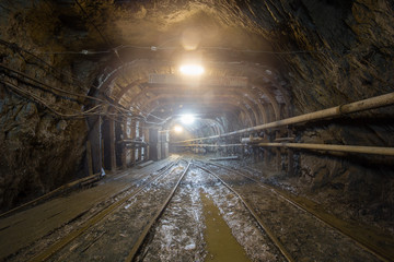 Underground gold mine tunnel with rails and light