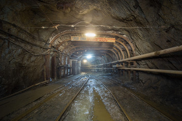 Underground gold mine tunnel with rails and light