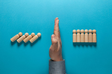 Hand of businessman in suit stops falling figures of people (employees), domino effect. Finance...