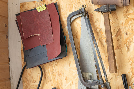 Joiner's workshop. Joiner's tools. Knives, file and hammer on a magnetic tape on the wall. Sandpaper