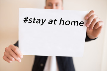 Guy holding a white sheet with the hashtag inscription Stay home