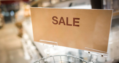 Sale tag of offering special promotion hanging in shopping mall, Blurred department store background.