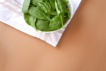 Plate of raw fresh spinach leaves on beige background