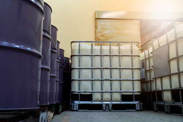 Low light inside of the old factory. Low view of large white and purple tanks chemical packaging with flare.