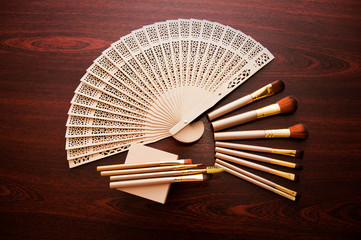 Many makeup brushes and little box on the wooden background