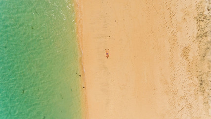 Aerial background top view of a man lying on a large beach. Pandawa beach, Bali, Indonesia.