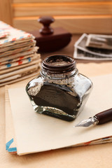 Stack of vintage letters, pen and inkwell on a wooden table