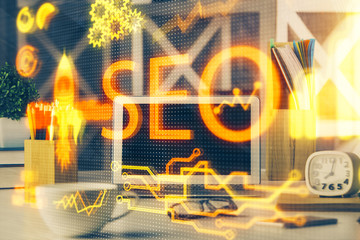 Double exposure of table with computer and seo drawing hologram. Search optimization concept.