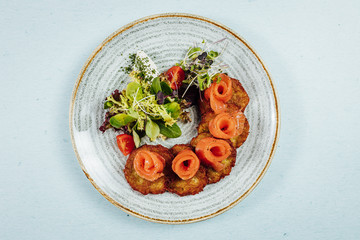 Beautifly served potato pancakes with salmon on bright table
