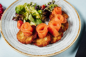 Beautifly served potato pancakes with salmon on bright table