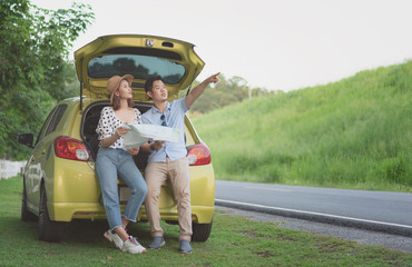 Asian teenage couples parked on the roadside, search for tourist spots on the map. Couple traveling by car on summer. leisure, road trip, travel concept.