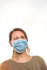 Coronavirus, blonde girl with protective mask against coronavirus. Pandemic COVID-19 concept. Light background with copy space.