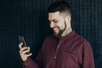 young bearded man with tattoo uses a mobile phone for video calling