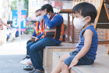 Little boy wear white mask protect Pm2.5 amd covid 19 sitting in cafe