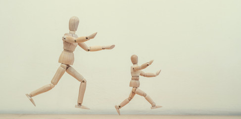 Concept - an adult runs after a child. Wooden men mannequins run after each other or run away, play with children.