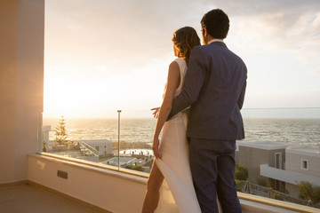 Young couple watching sunset by the sea