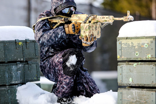 male paintballer in uniform and protective masks aiming by paintball guns outdoors.
