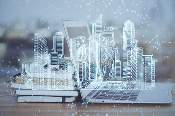 Desktop computer background in office and big town buildings hologram drawing. Double exposure. Smart city concept.