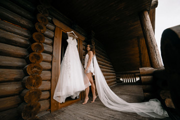 Romantic atmosphere of the bride's morning. Bride in a home. Bride morning preparation. Bride in beautiful dress near the mannequin with dress indoors at home. Enjoy every moment.