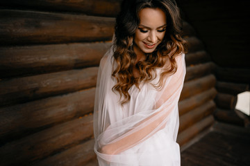 Fototapeta premium Romantic atmosphere of the bride's morning. Bride in a home. Bride morning preparation. Bride in beautiful dress near the mannequin with dress indoors at home. Enjoy every moment.