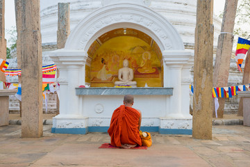 Buddhist monk meditates at Buddha sculpture. Dagoba Thuparama, Anuradhapura