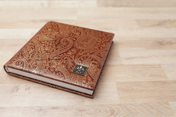 Photo book, notebook or diary with a cover of genuine leather. Brown color with decorative stamping. Wedding or family photo album. Copy space.