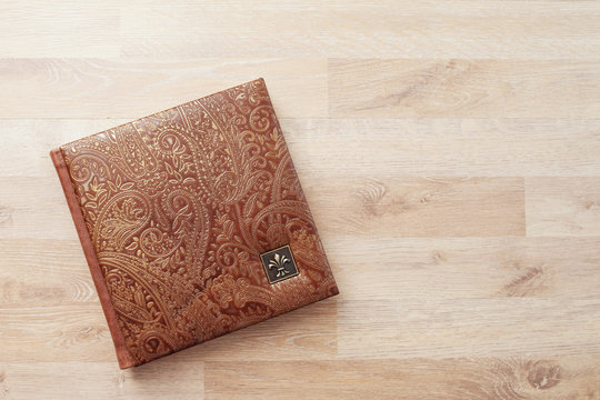 Photo book, notebook or diary with a cover of genuine leather. Brown color with decorative stamping. Wedding or family photo album. Copy space.