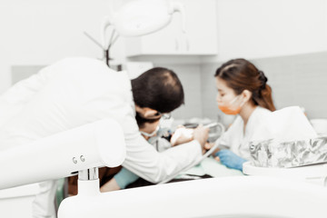 An intern dentist examines a patient under the supervision of a mentor. Professional uniform and equipment of a dentist. Healthcare Equipping a doctor’s workplace. Dentistry.