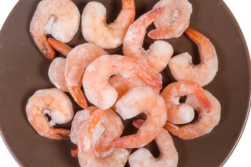 Prawn tails in ice glazing on brown dish, top view