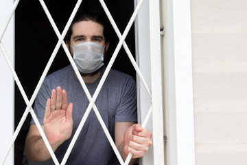 male model in a disposable mask, dark hair, beard and grey t-shirt.A coronavirus patient remains at...