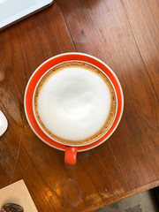 Top view of hot cappuccino with milk foam on wood table in coffee shop