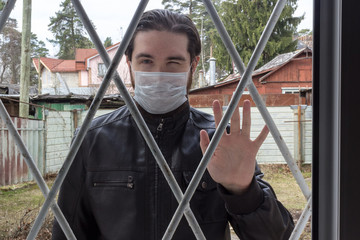 male model in a disposable mask, dark hair, beard and leather jacket. A coronavirus patient has run away from home and is a danger to society.Stay at home and strengthen your immune system